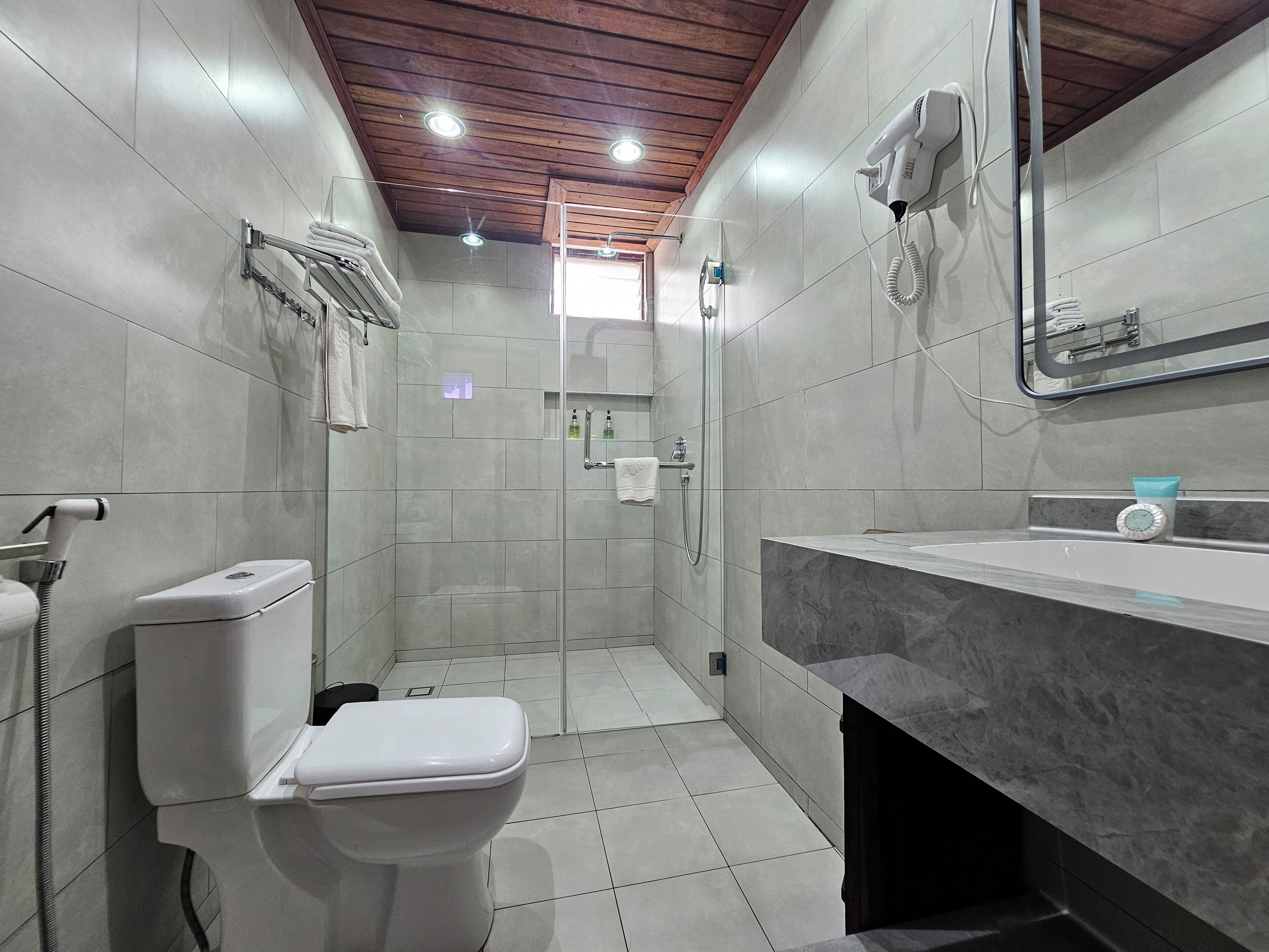 A modern bathroom with a toilet, shower, and sink.