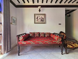 Un sofá tradicional con tapicería estampada en una habitación con suelo de baldosas y techo con vigas a la vista.