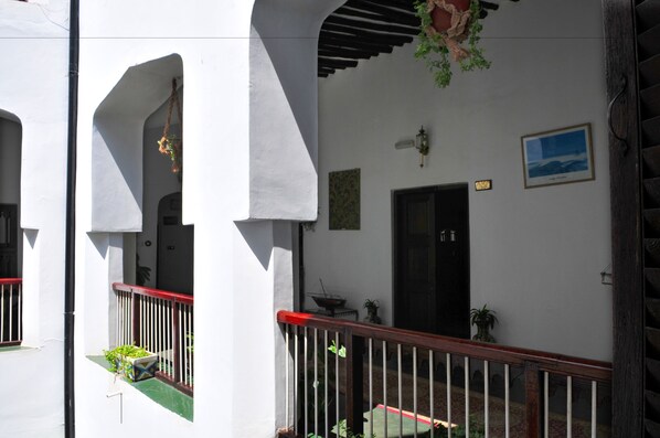 A white building with a balcony, a door, and a small garden area. - Dhow Palace Hotel (Zanzibar Town)
