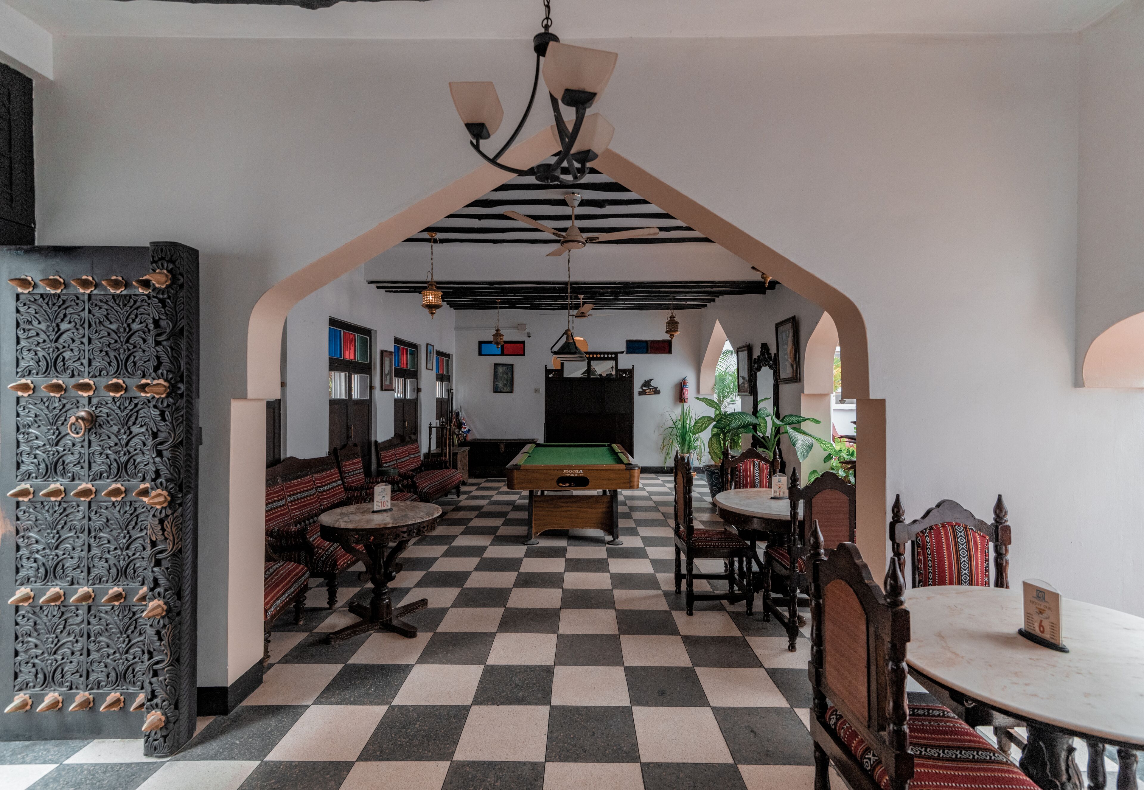 A billiards room with a checkered floor, pool table, and seating area.