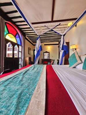 A room with a bed, a canopy, a stained glass window, and a lamp. - Dhow Palace Hotel (Zanzibar Town)