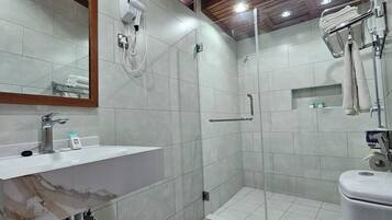 Un baño moderno con lavamanos de mármol, inodoro, ducha con puerta de vidrio y techo de madera.
