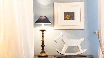 A room with a lamp, a framed picture, and a rocking horse.