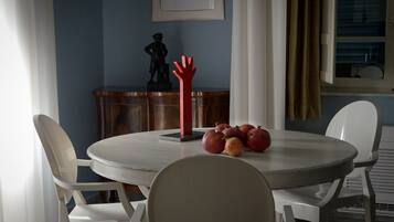 A dining area with a round table, white chairs, and a pomegranate centerpiece.