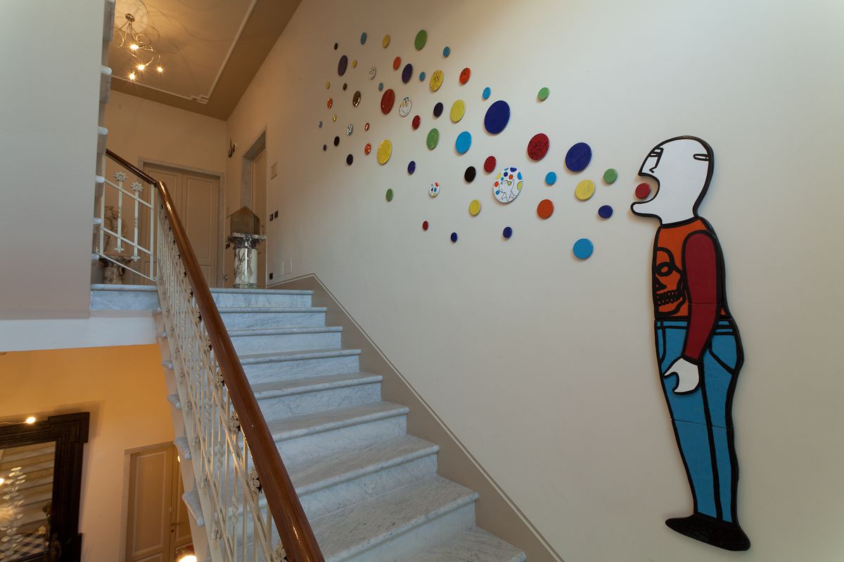Eine Treppe mit Handlauf und Wand, verziert mit bunten, kreisförmigen Mustern und einer ausgeschnittenen Figur.