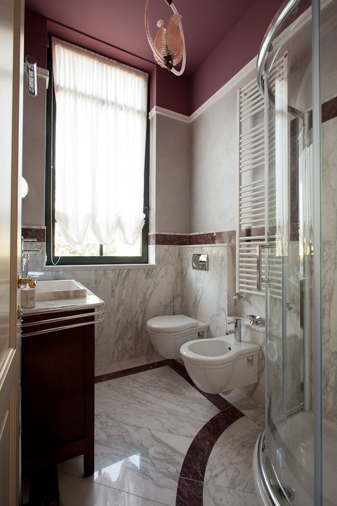 Un baño con cabina de ducha de vidrio, un bidé, un inodoro y un lavabo con encimera de mármol.