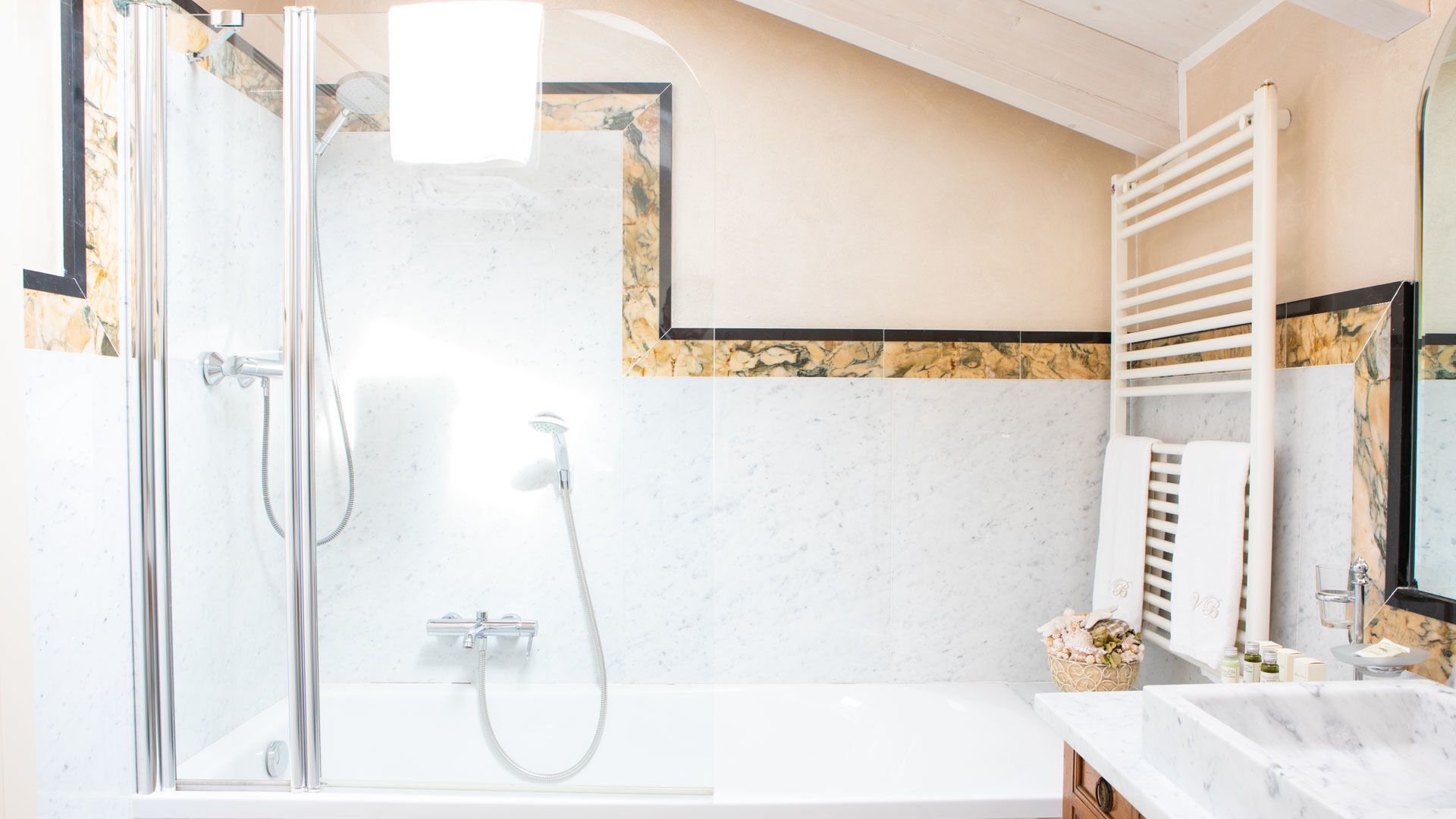 Un baño moderno con ducha envuelta en vidrio, una bañera blanca y un revestimiento de mármol.
