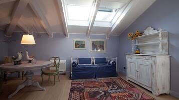 A room with a skylight, a blue sofa, a white cabinet, and a patterned rug.