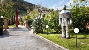 A garden pathway leading to a building with a large statue. - Villa Belverde (Carrara)