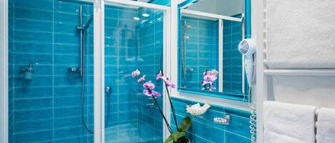 Ein Badezimmer mit blauen Fliesen, einem weißen Waschbecken, einem Spiegel und einem Haartrockner.