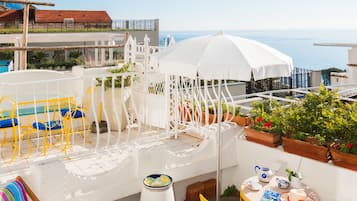 Enjoy breathtaking sea views from this rooftop terrace, featuring a charming seating area with a teapot and potted plants.