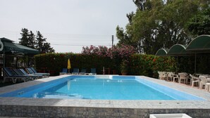 Una piscina con sillones de descanso y una zona de estar techada.