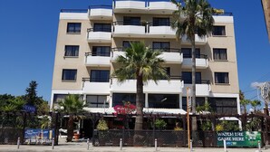 Un hotel de varios pisos con balcones, una palmera y un cartel de una atracción turística.