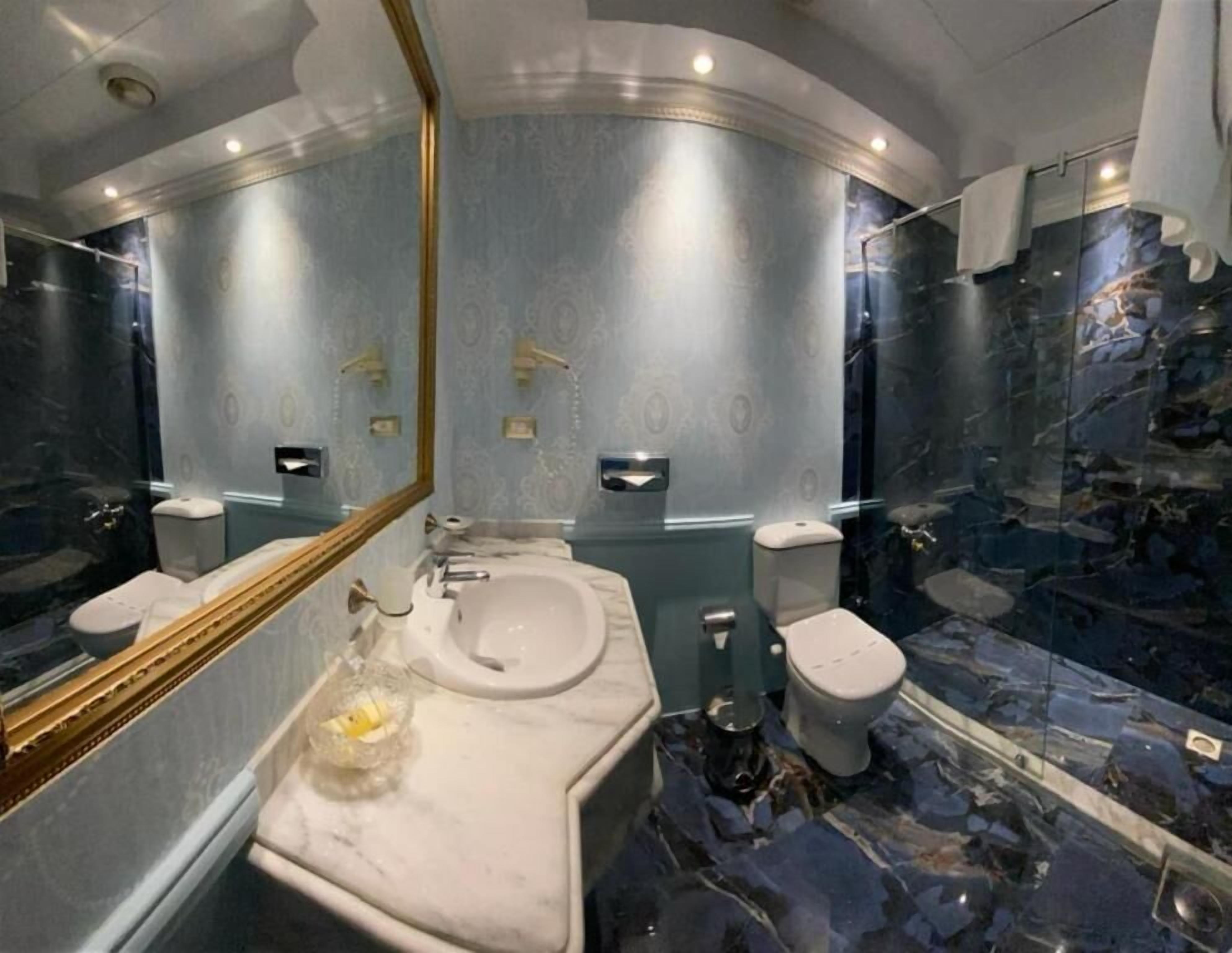 Une salle de bain avec un sol en marbre, un lavabo, des toilettes et un miroir.