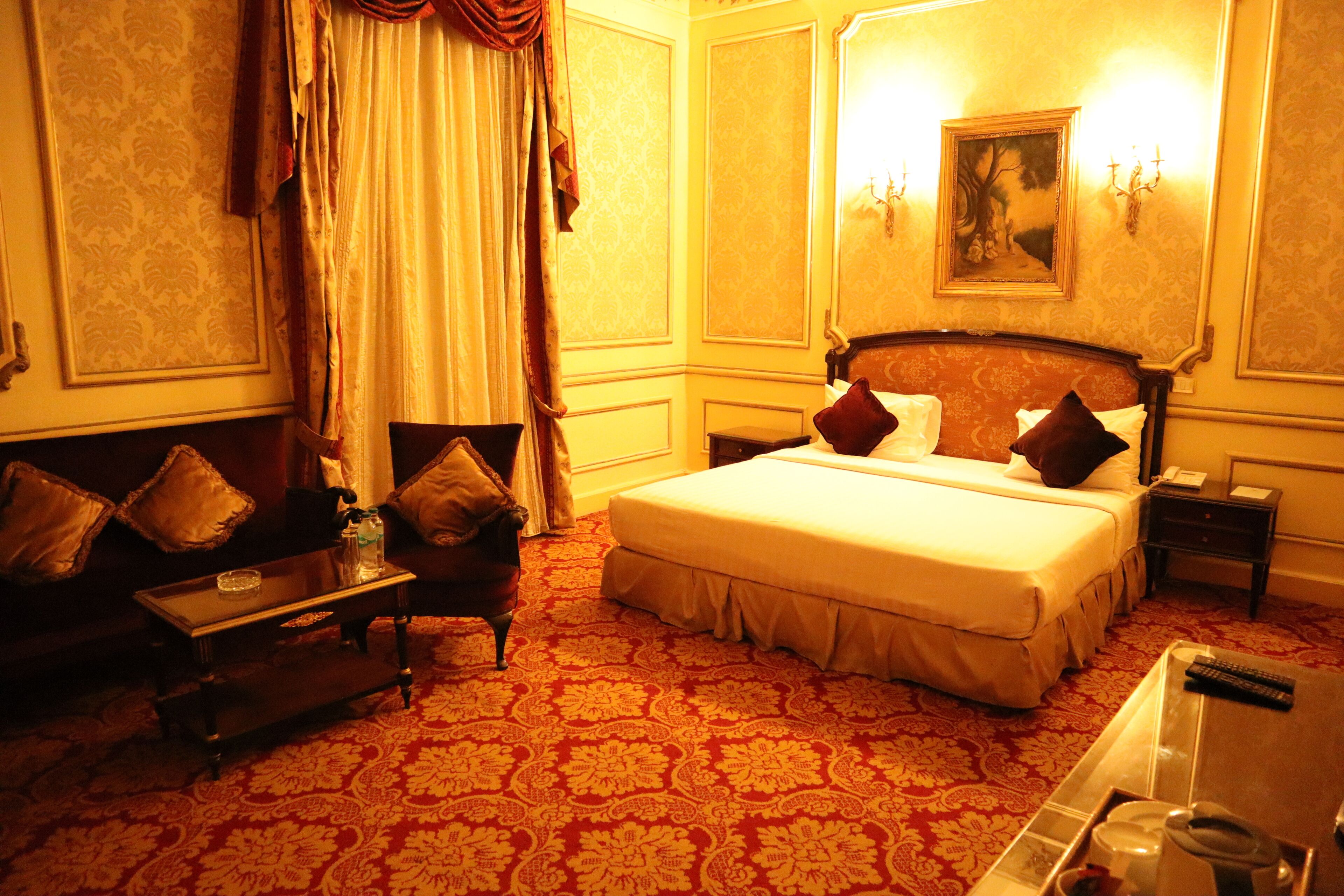 Una habitación de hotel con una cama grande, una mesita de noche, un sillón y un sofá.