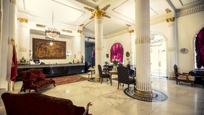 A grand lobby with marble floors, classical columns, and elegant furniture.