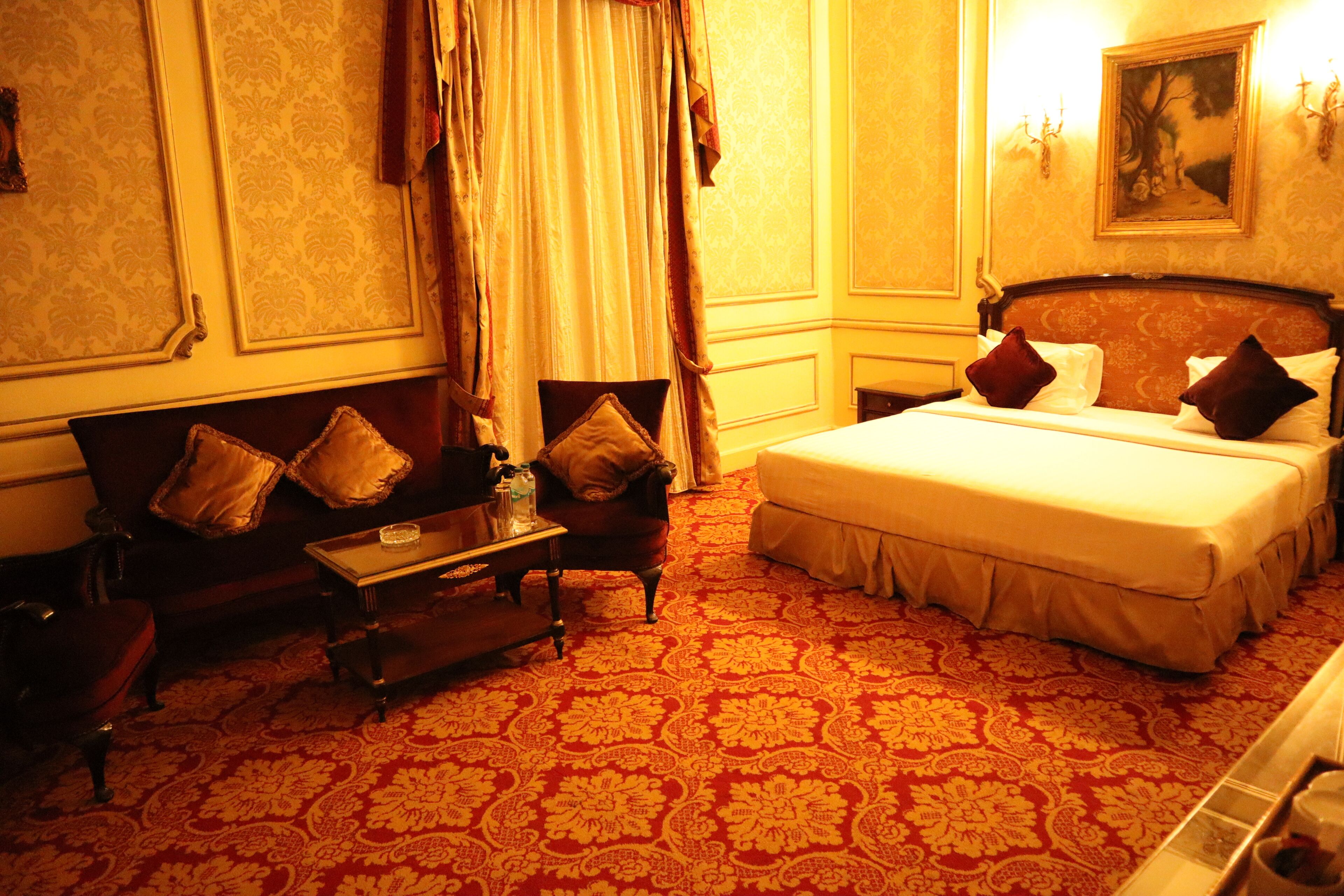 A hotel room with a large bed, a sofa, a small table, and a chair.