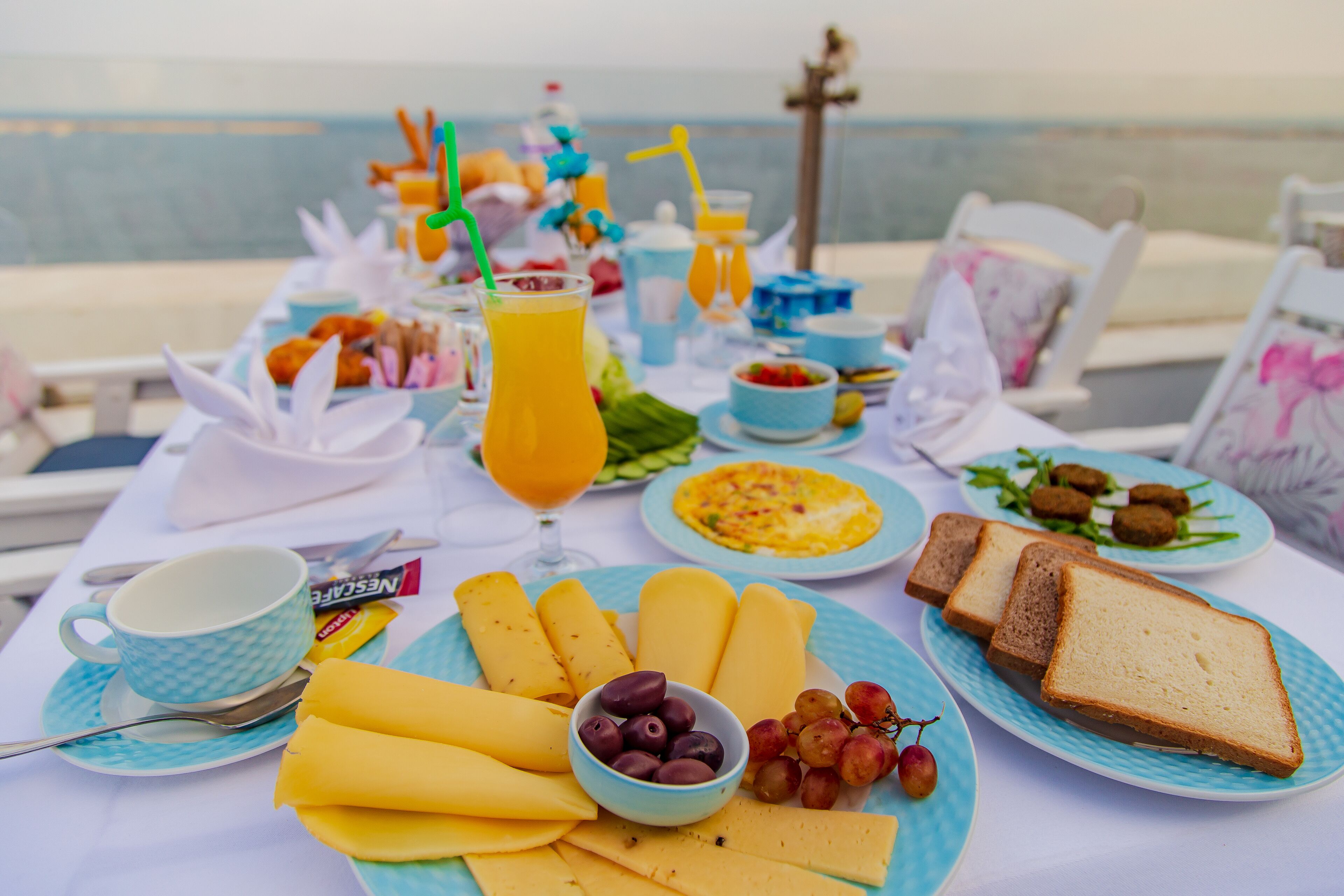A breakfast table with plates of food, a bowl of grapes, and a glass of orange juice.