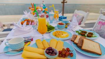 A breakfast table with plates of food, a bowl of grapes, and a glass of orange juice.