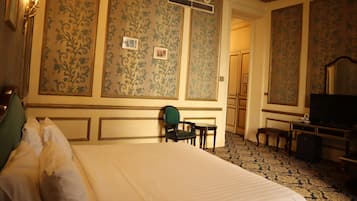 A hotel room with a large bed, a desk, a chair, and a television.