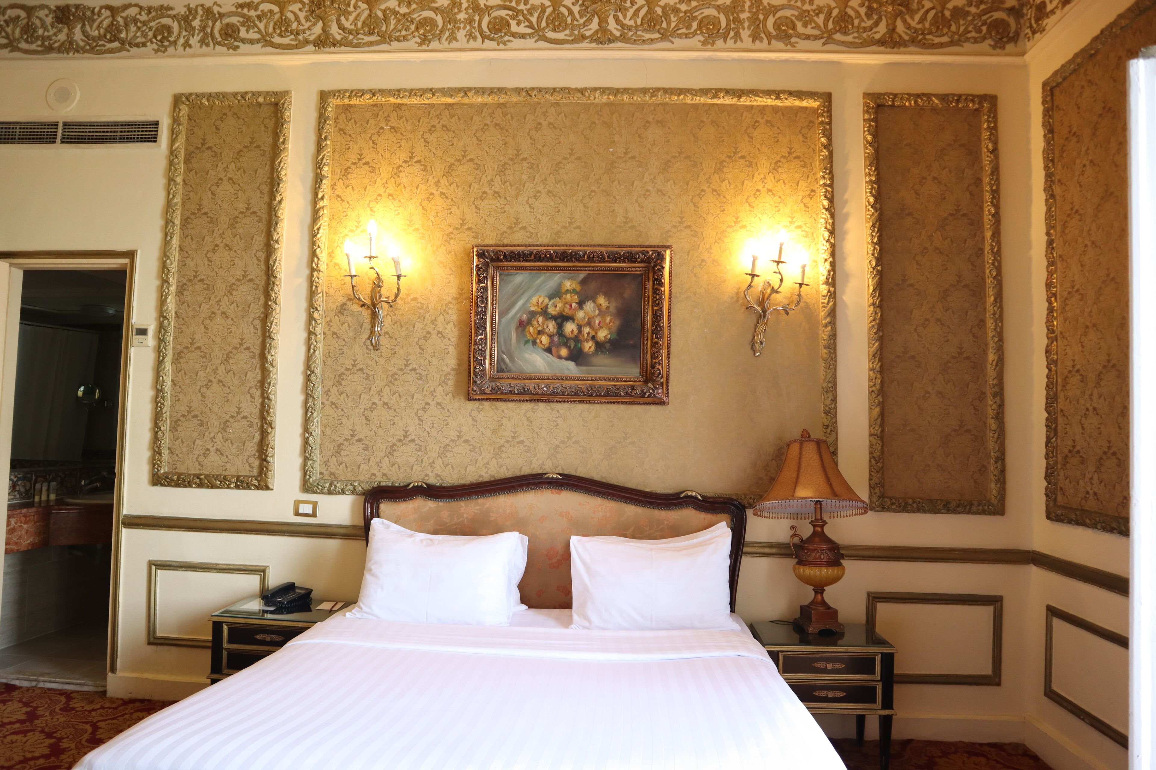 Una habitación de hotel con una cama grande, dos mesitas de noche, una lámpara y un cuadro en la pared.