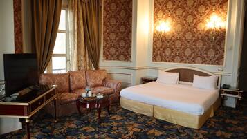 Une chambre d’hôtel avec un grand lit, un canapé, une télévision et une petite table avec un plateau.