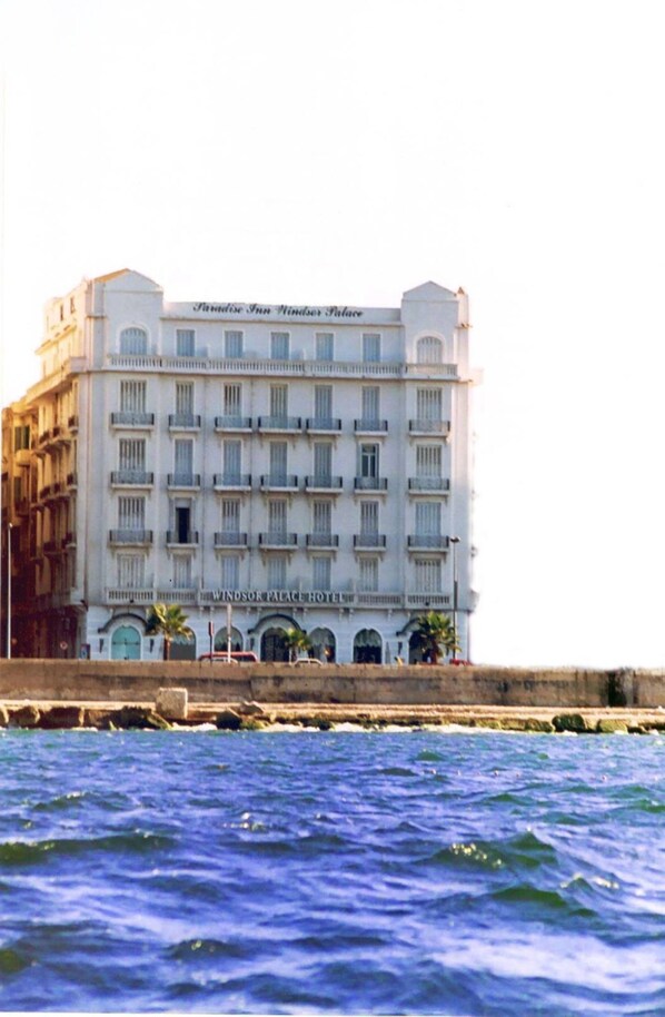 A multi-story hotel with a classic architectural style, featuring a prominent entrance with arches and a balcony on the second floor. - Windsor Palace Luxury Heritage Hotel Since 1906 by Paradise Inn Group (Alexandria)