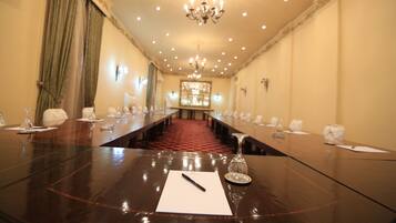 Ein Konferenzraum mit langem Tisch, Stühlen und einer Chandelier.