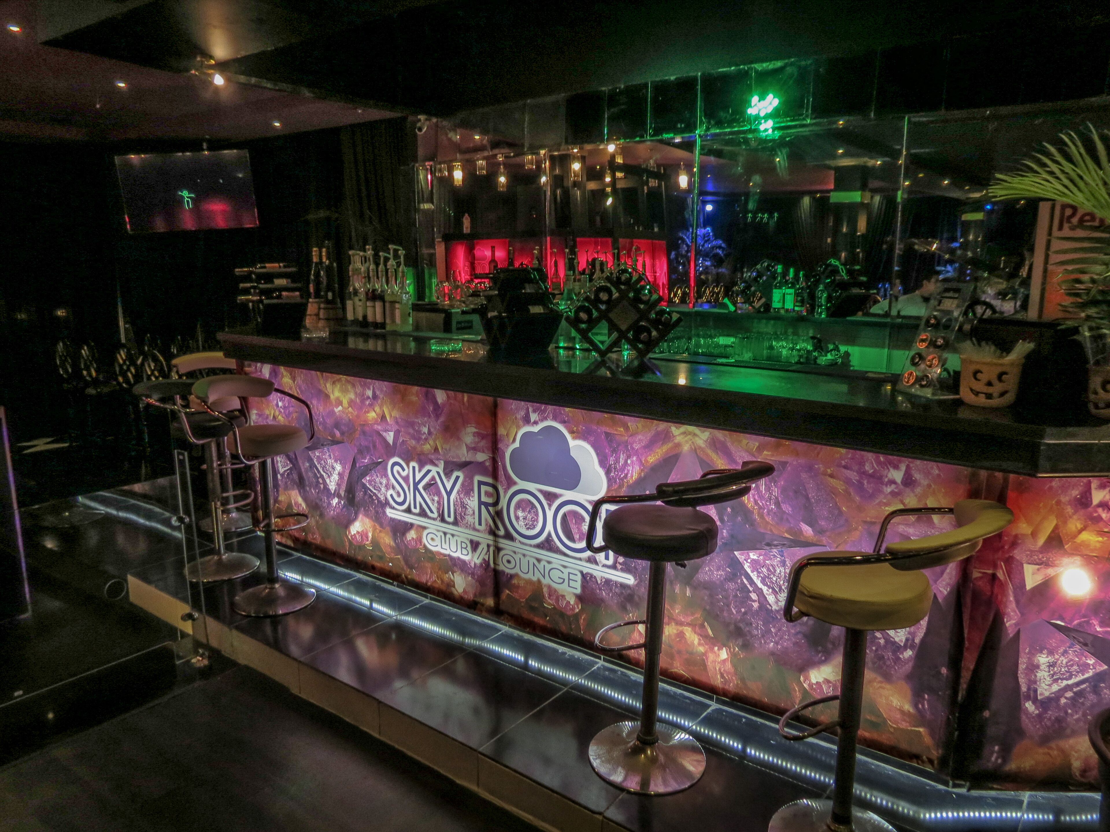 Zona bar con insegna al neon che riporta la scritta "SKY ROOM CLUB LOUNGE".