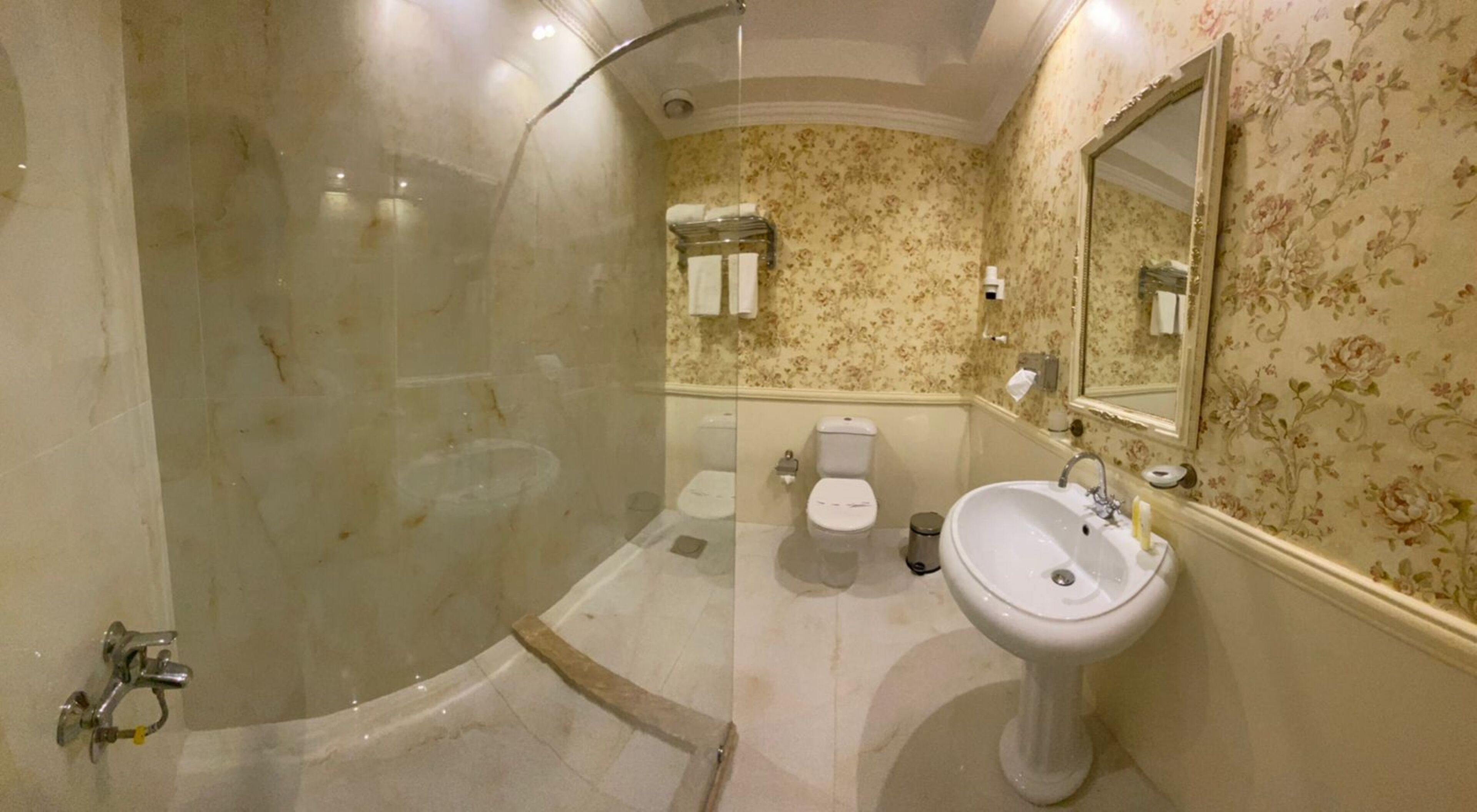 A bathroom with a glass-enclosed shower, a sink, and two toilets.