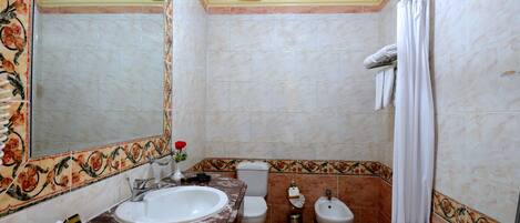 A bathroom with a sink, toilet, bidet, and bathtub.