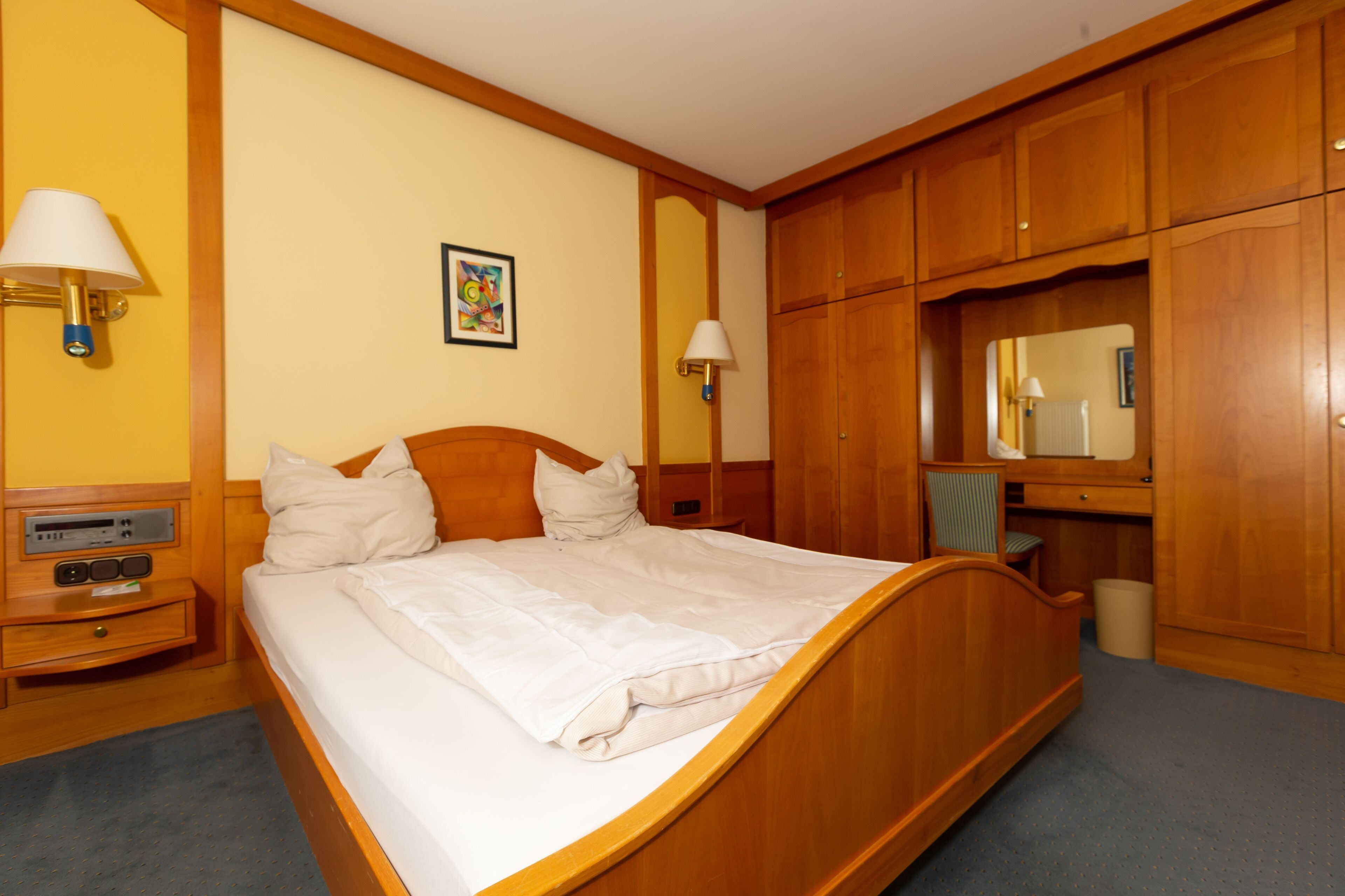 A hotel room with a wooden bed, a desk, and a chair.