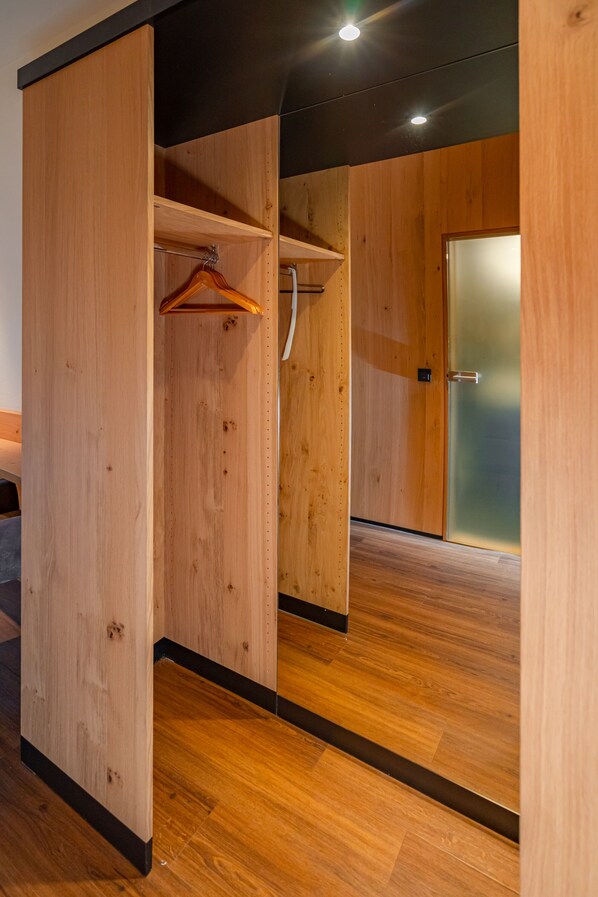 A wooden room with a wooden wardrobe, a hanging rack, and a door with frosted glass. - Parkhotel Traunstein (Traunstein)