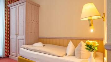 Una habitación de hotel con cama, mesita de noche, lámpara, armario y cortina.