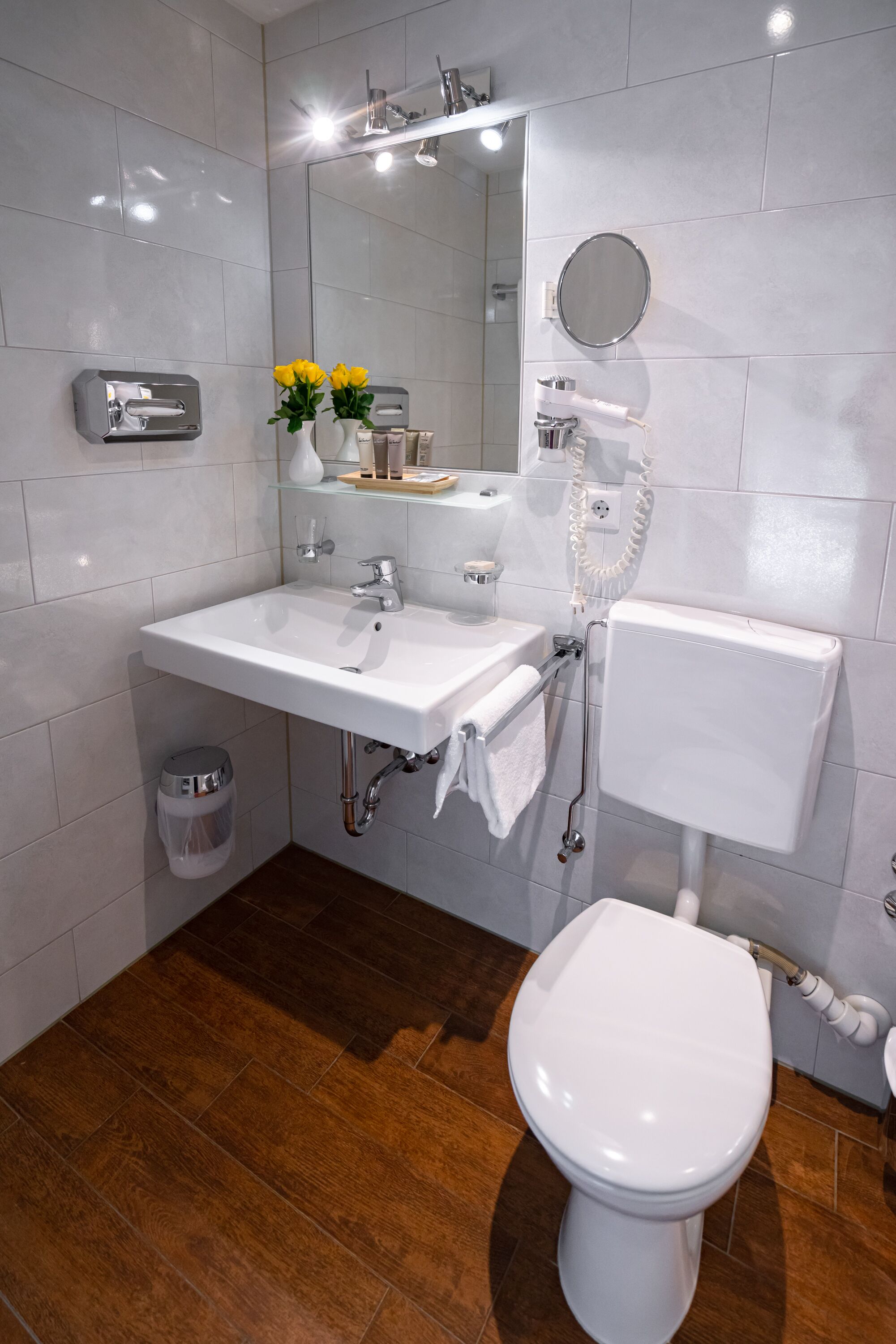 A modern bathroom with a white sink, mirror, and toilet.