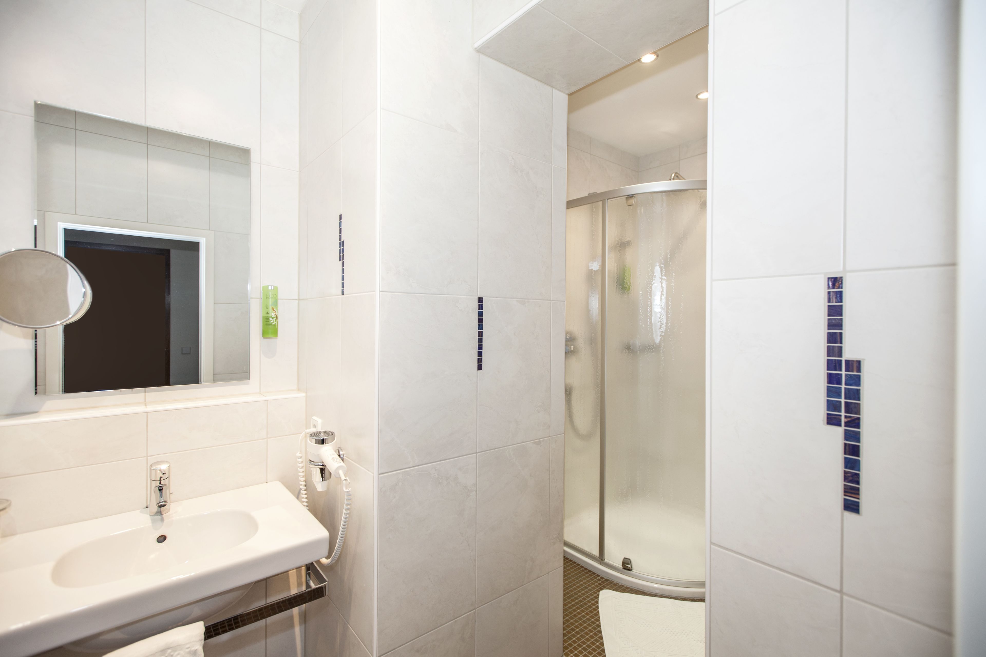 A bathroom with a sink, mirror, and shower.