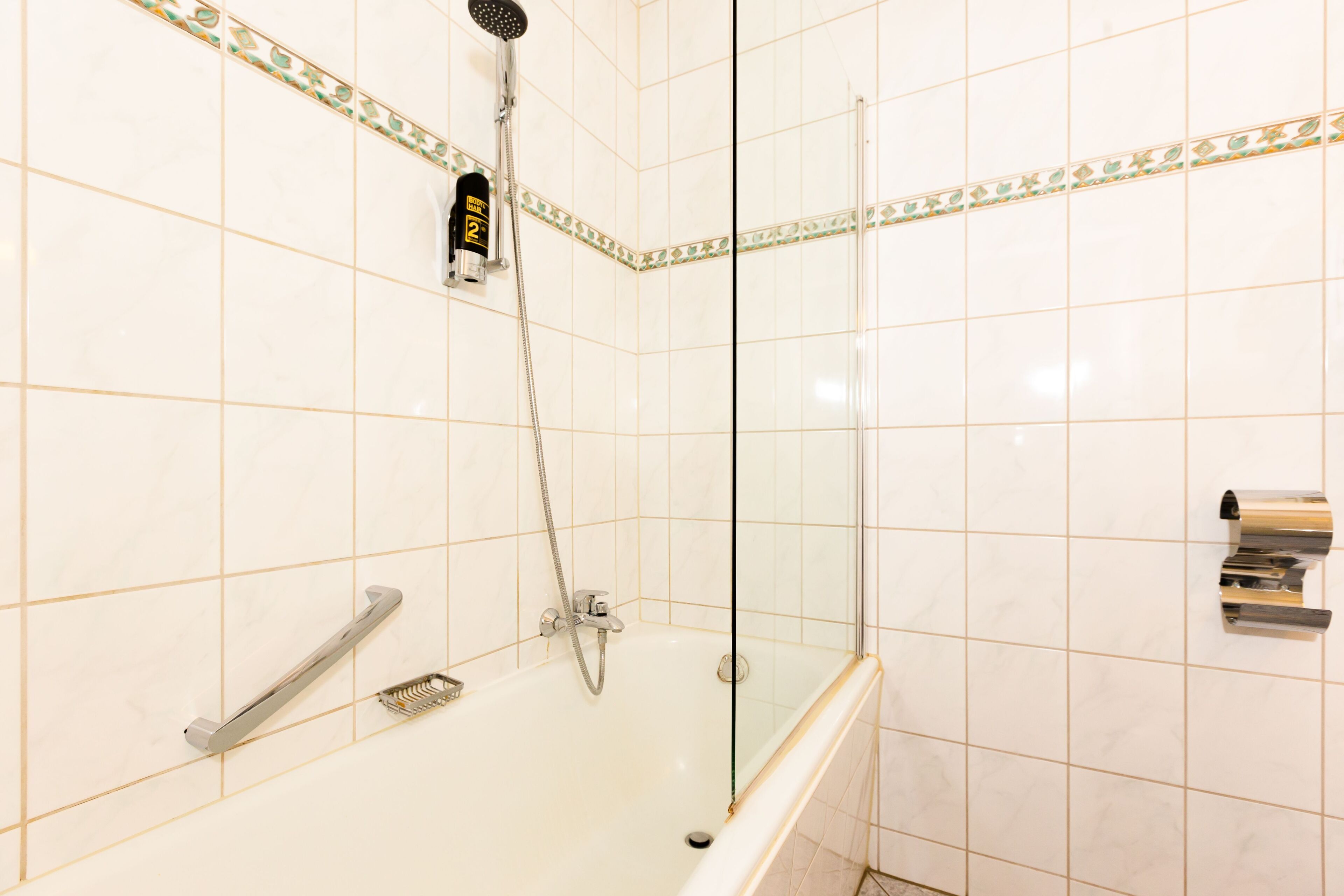 Une salle de bain moderne dotée d’une douche à parois de verre, d’une baignoire avec un pommeau de douche amovible et d’un porte-serviettes.