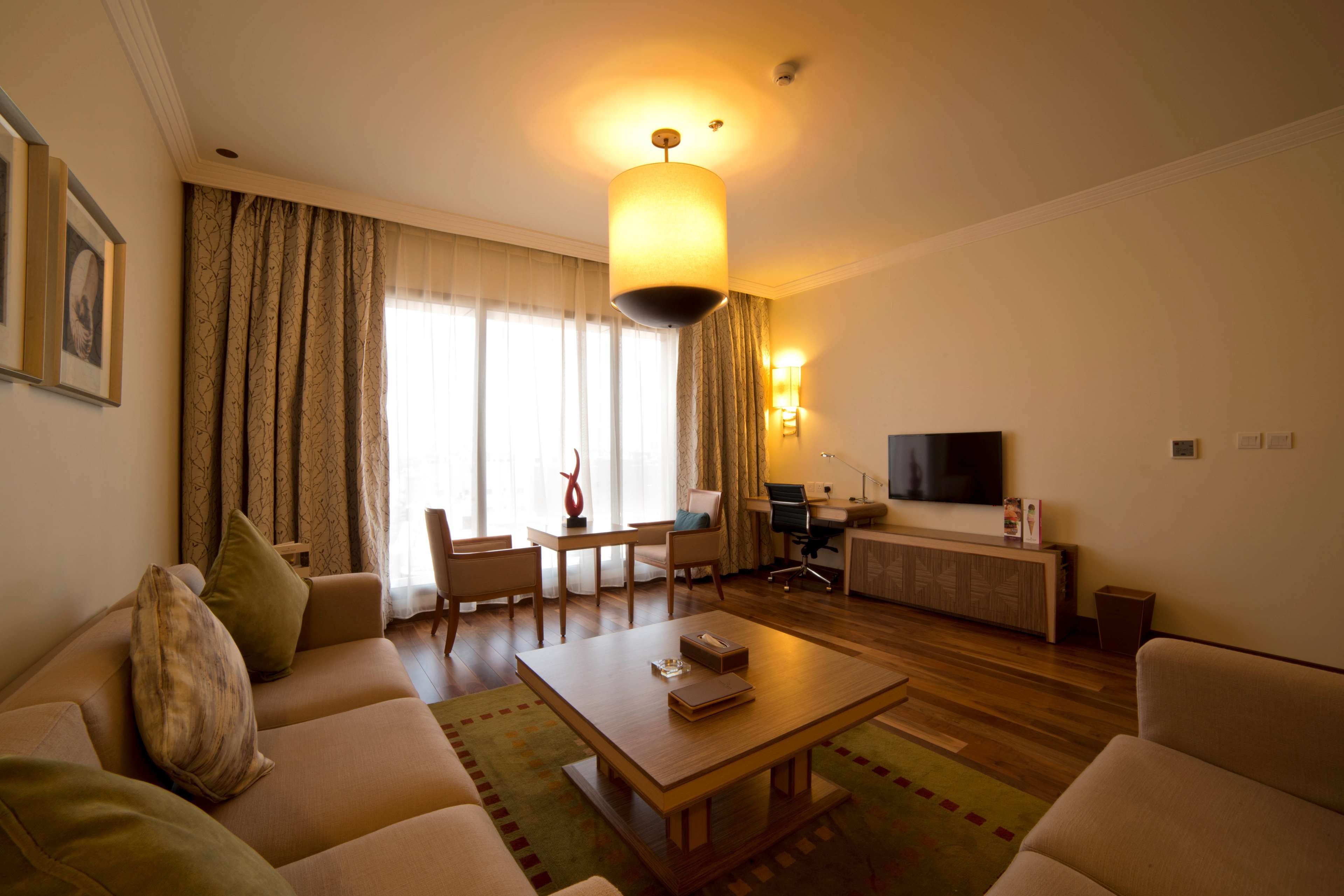 A modern living room with a sofa, coffee table, and a dining area with chairs and a table.