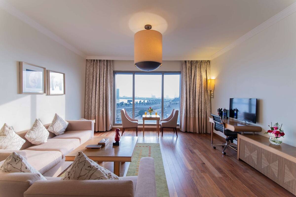 Ein modernes Wohnzimmer mit Sofa, Couchtisch, Fernseher und Blick auf die Stadt.