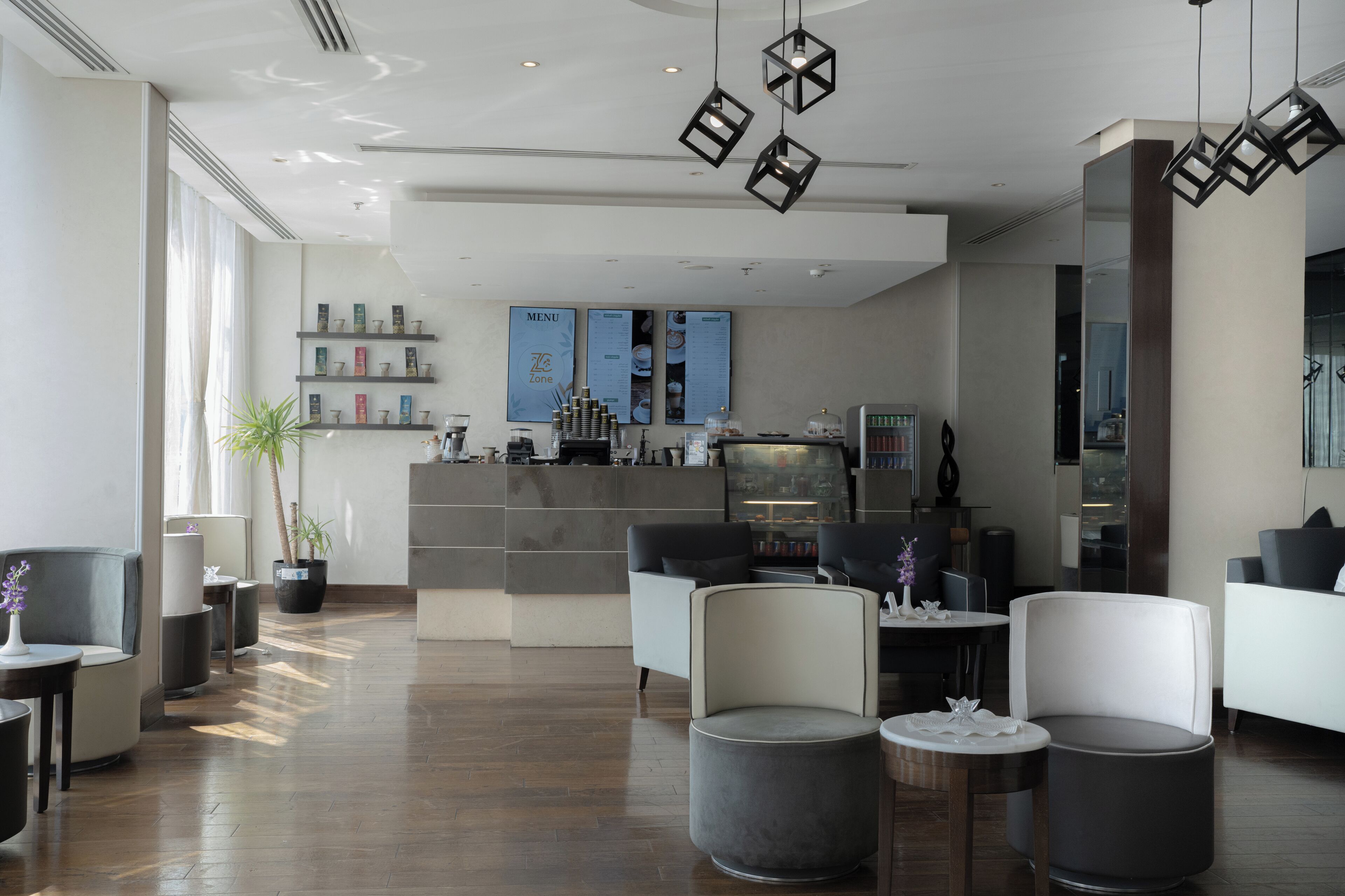 A modern lobby with seating areas, a reception desk, and a menu board.