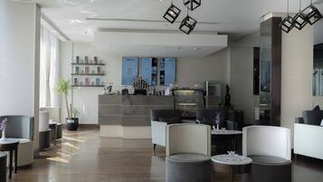 A modern lobby with seating areas, a reception desk, and a menu board.