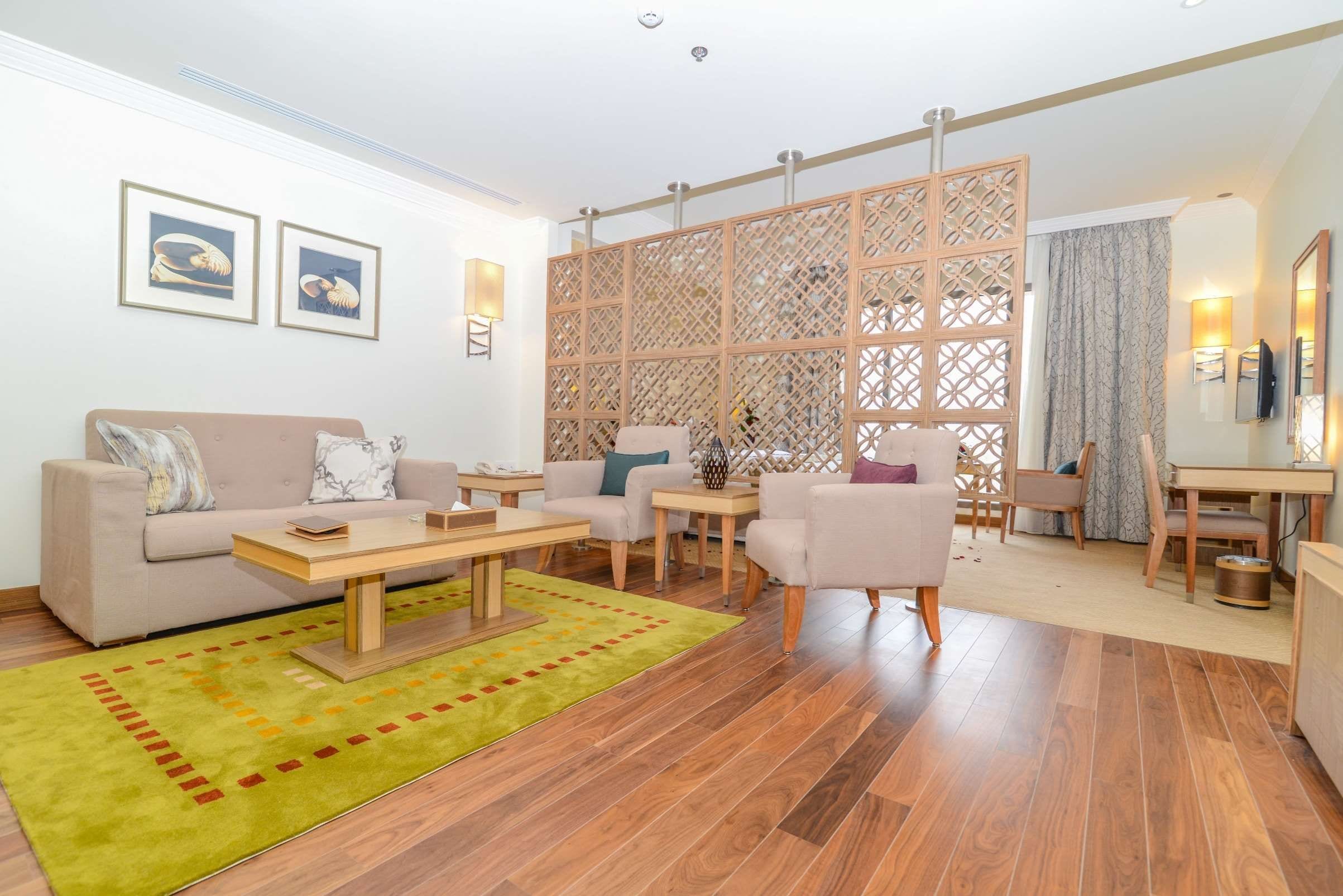 A modern living room with a sofa, armchairs, a coffee table, and a decorative partition.
