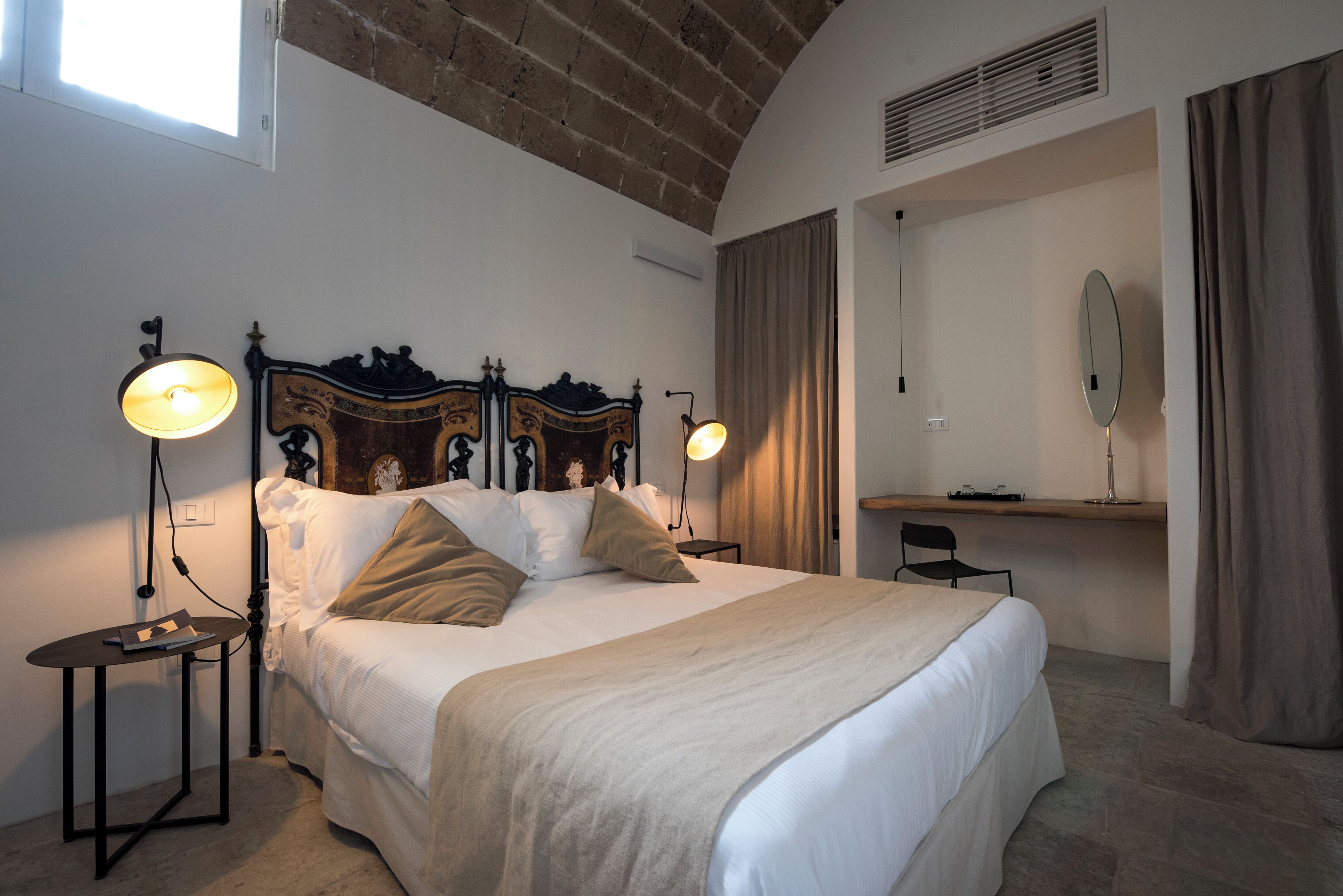 Une chambre à coucher avec un lit, des lampes de chevet, un bureau, une chaise et un miroir.
