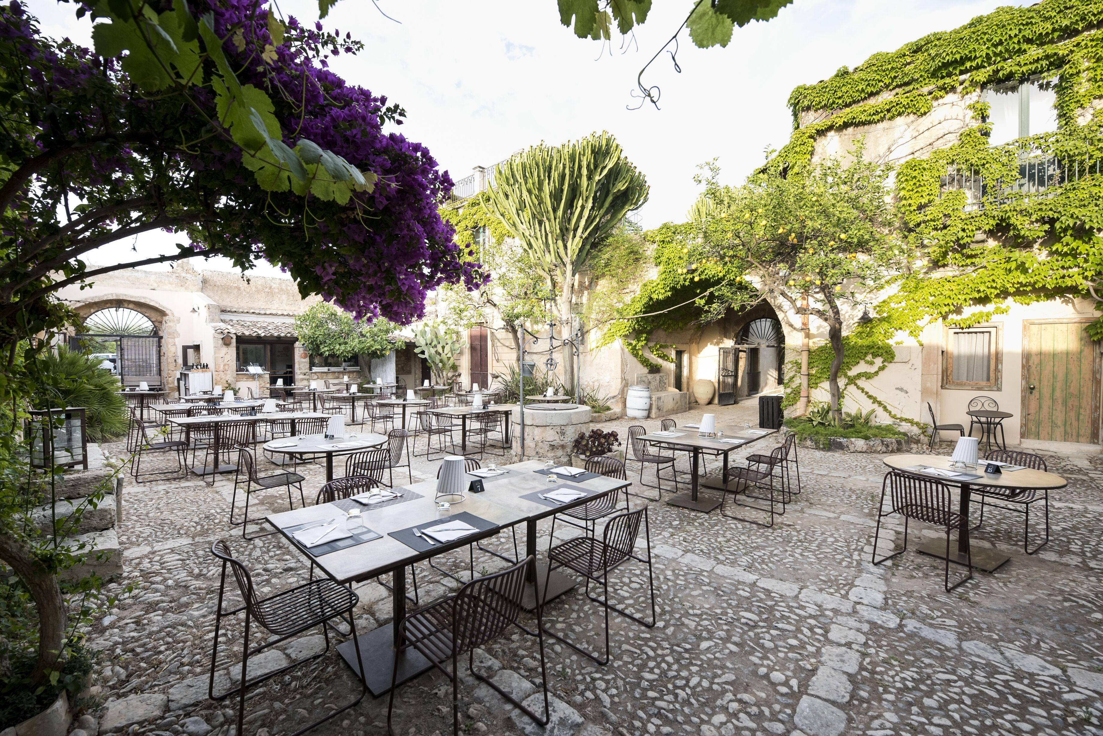 Eine Terrasse im Freien mit Steinboden und Tischen, die zum Essen bereitstehen.