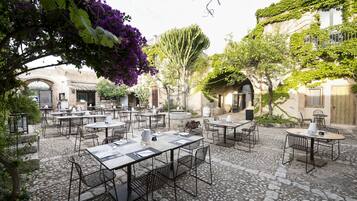 Eine Terrasse im Freien mit Steinboden und Tischen, die zum Essen bereitstehen.