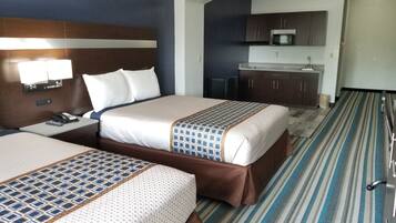 A hotel room with two beds, a kitchenette, and a bathroom.