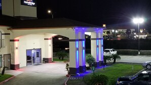 A hotel entrance with a covered waiting area, a fire lane, and a parking lot. - HomeBridge Inn and Suites (Beaumont)