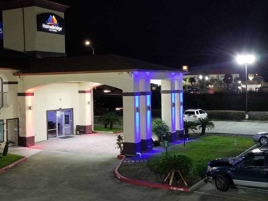 A hotel entrance with a covered waiting area, a fire lane, and a parking lot.