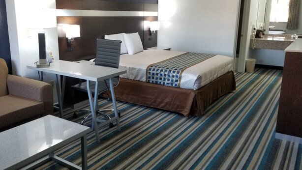 A hotel room with a bed, a desk, a chair, a sofa, and a bathroom.