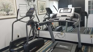 A gym with treadmills and a stationary bike, a mirror, and framed artwork on the wall. - HomeBridge Inn and Suites (Beaumont)